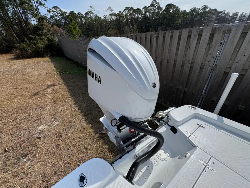 Slide: The Image of Outboard motor on a 2025 BlackJack 224 boat, parked near a wooden fence. - 15