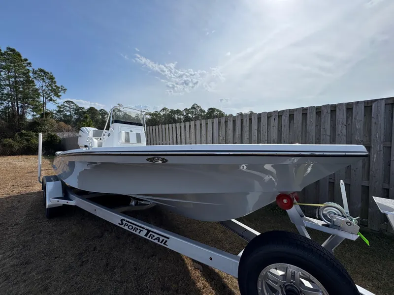 Slide: The Image of 2025 BlackJack 224 boat on Sport Trail trailer, parked outdoors near wooden fence. - 4