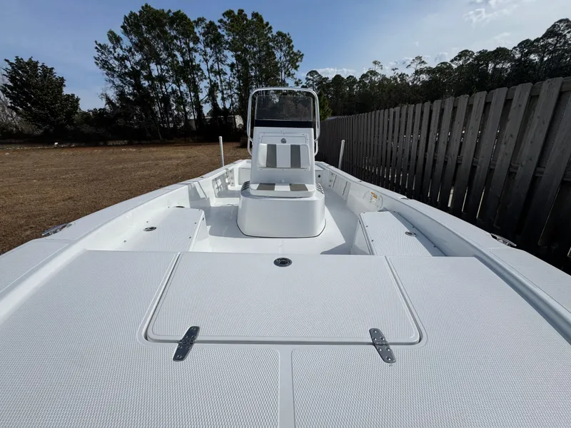 Slide: The Image of 2025 BlackJack 224 boat with sleek white deck, surrounded by trees and a wooden fence. - 7