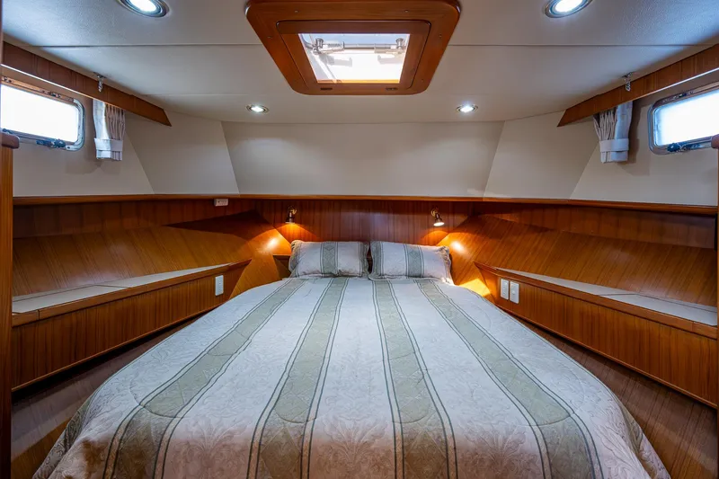 Slide: The Image of Luxurious cabin interior of a 2002 Symbol 42' yacht with cozy bedding and wood paneling. - 23