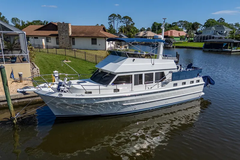 Slide: The Image of 2002 Symbol 42' yacht docked in a serene residential canal setting. - 3