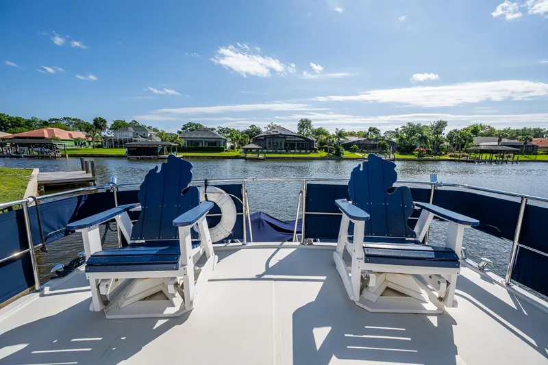 Slide: The Image of Deck view of a 2002 Symbol 42' yacht with blue chairs overlooking a serene waterfront. - 38