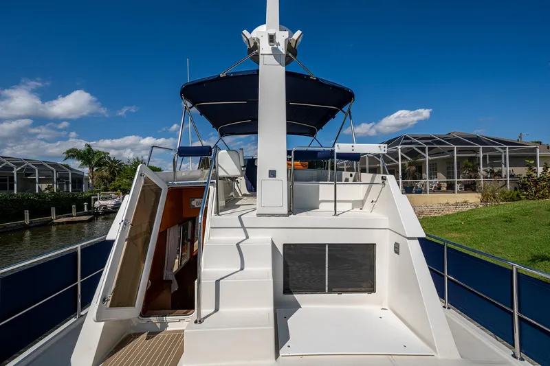 Slide: The Image of 2002 Symbol 42' yacht with blue canopy, docked near waterfront homes. - 39