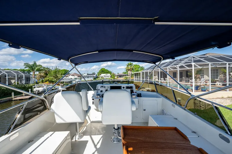 Slide: The Image of 2002 Symbol 42' yacht cockpit with canopy, featuring dual white captain chairs and waterfront view. - 41