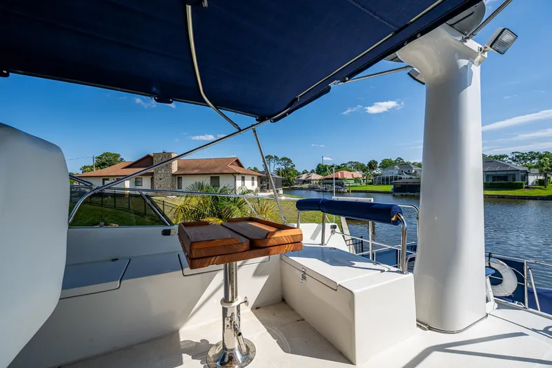 Slide: The Image of 2002 Symbol 42' yacht deck with seating and table, overlooking waterfront homes. - 42