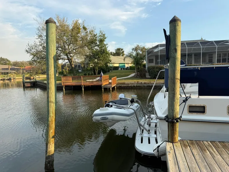 Slide: The Image of Docked 2002 Symbol 42' yacht with dinghy on calm water near residential area. - 43