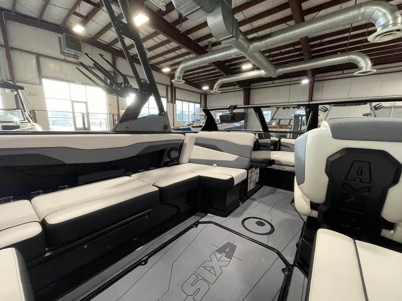 Slide: The Image of 2025 Axis T220 boat interior with modern seating and sleek design in a spacious showroom. - 15