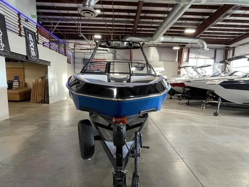 Slide: The Image of 2025 Axis T220 boat in showroom, blue exterior, on trailer, industrial setting. - 4