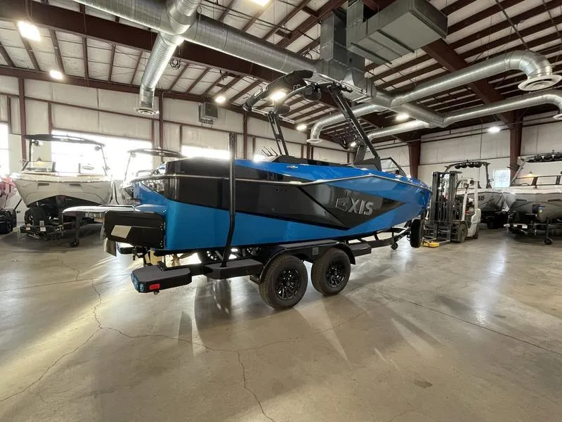 Slide: The Image of 2025 Axis T220 boat in a showroom, featuring a sleek blue and black design. - 6