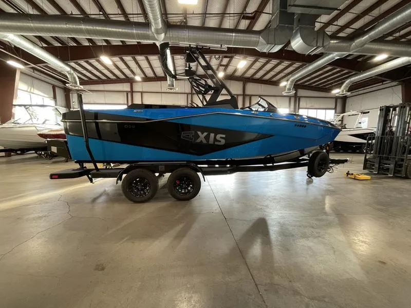 Slide: The Image of 2025 Axis T220 boat in a warehouse, blue and black design, on a trailer. - 7