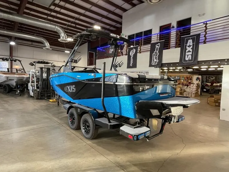 Slide: The Image of 2025 Axis T220 boat in showroom, blue and black design, on trailer. - 9
