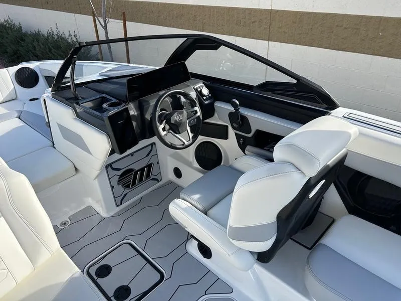 Slide: The Image of 2025 Malibu 23 MXZ boat interior with sleek white seating and modern dashboard design. - 13
