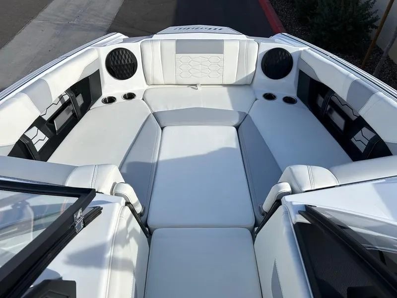 Slide: The Image of 2025 Malibu 23 MXZ boat interior with white seating and cup holders. - 14