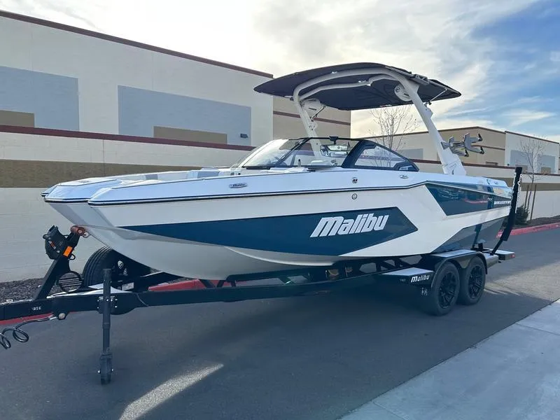 Slide: The Image of 2025 Malibu 23 MXZ boat on trailer, parked outdoors, featuring sleek design and modern features. - 3
