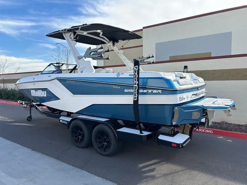 Slide: The Image of 2025 Malibu 23 MXZ boat on trailer, blue and white design, parked outdoors. - 4