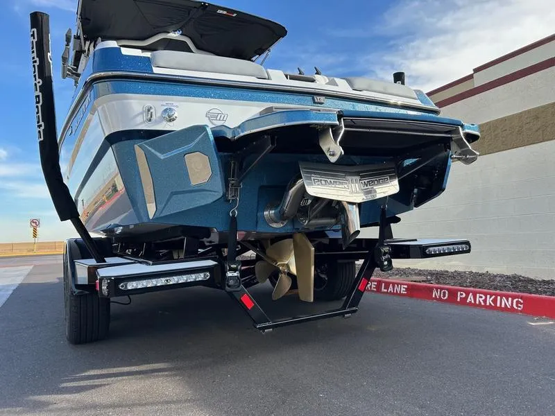 Slide: The Image of 2025 Malibu 23 MXZ boat on trailer, rear view, parked near "No Parking" zone. - 5