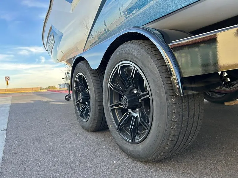 Slide: The Image of 2025 Malibu 23 MXZ boat trailer with black wheels on pavement. - 6