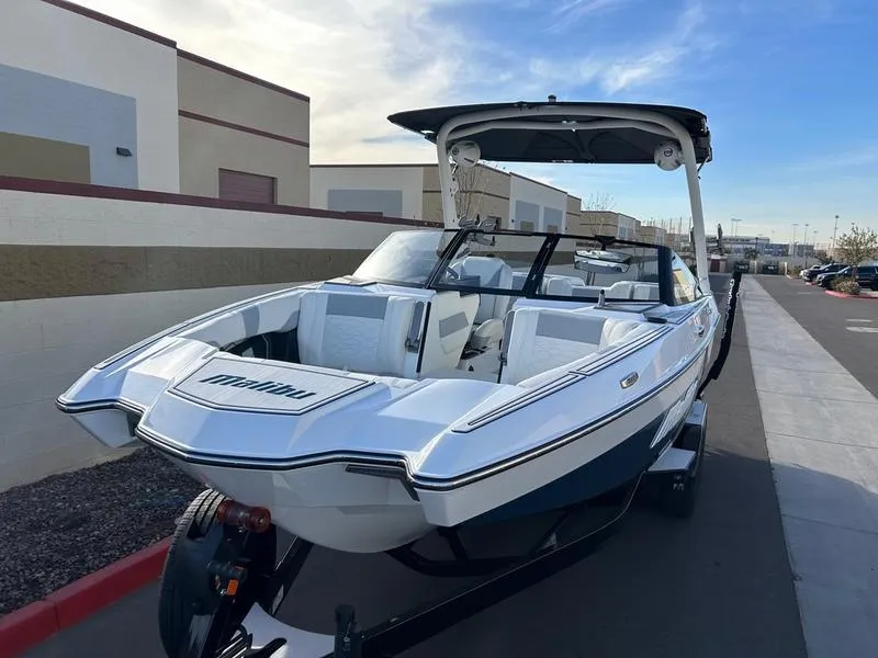 Slide: The Image of 2025 Malibu 23 MXZ boat on trailer, parked outdoors, showcasing sleek design and modern features. - 7