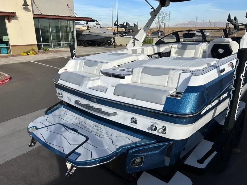 Slide: The Image of 2025 Malibu 23 MXZ boat with sleek design and spacious seating, parked outdoors. - 8