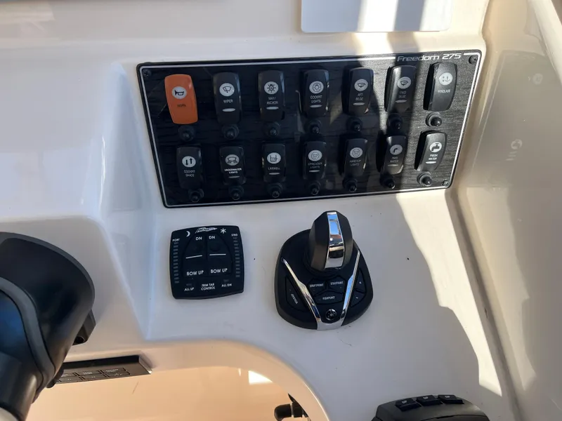 Slide: The Image of Control panel of 2023 Grady-White Freedom 275 boat with various switches and joystick. - 38