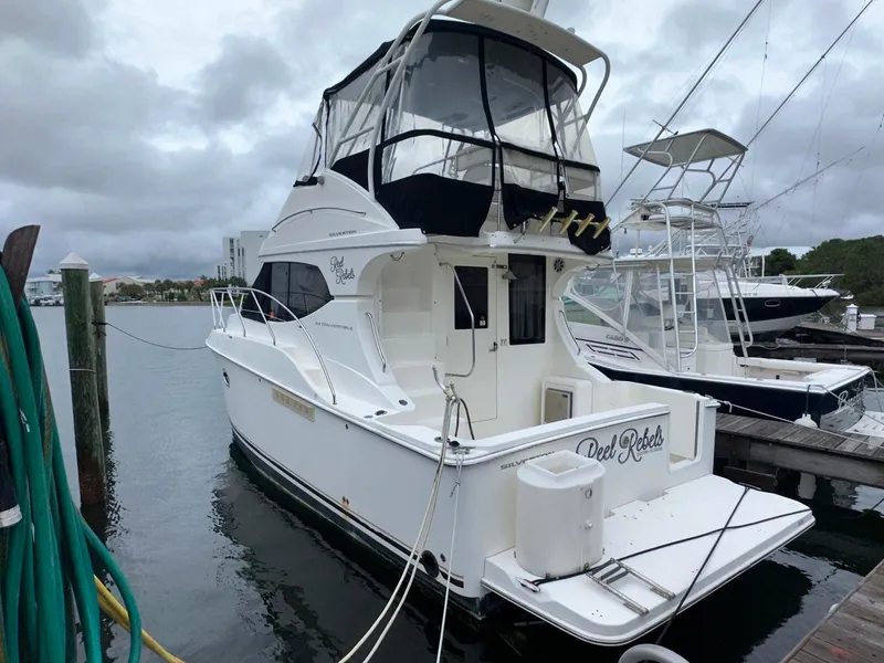 Slide: The Image of 2007 Silverton 330 Sport Bridge yacht docked at marina under cloudy skies. - 0