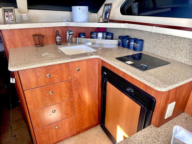 Slide: The Image of 2007 Silverton 330 Sport Bridge kitchen with wood cabinets, sink, and mini fridge. - 14