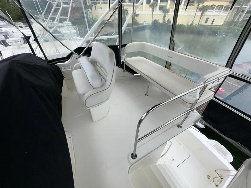 Slide: The Image of 2007 Silverton 330 Sport Bridge interior with white seating and railing, docked by the water. - 9