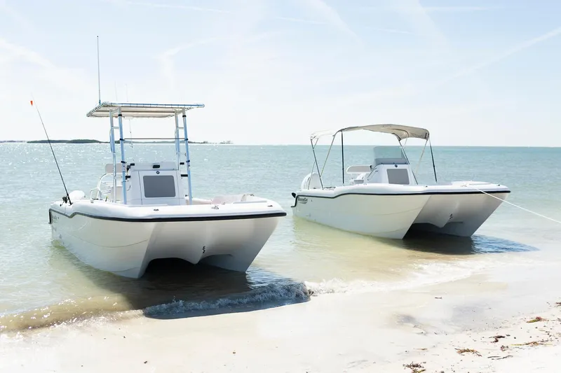 Slide: The Image of Two 2025 ArrowCat 20 CC boats on a sandy beach, calm ocean backdrop. - 5