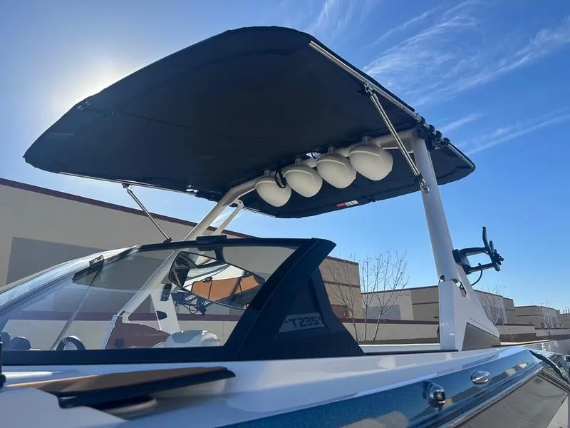 Slide: The Image of 2025 Axis T235 boat with canopy and speakers under a clear blue sky. - 7