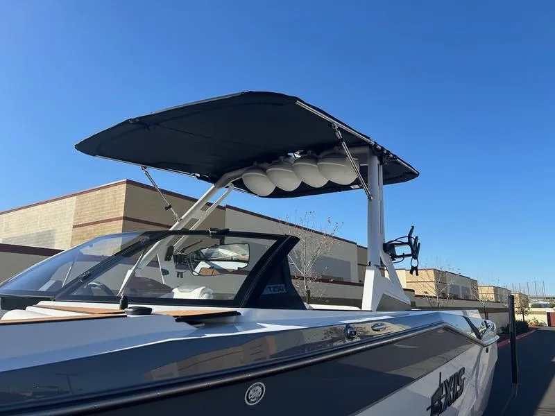 Slide: The Image of 2025 Axis T250 boat with canopy, parked outdoors under clear blue sky. - 7