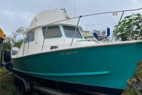 The Image of 1988 Robertson Sportfish boat with teal hull on trailer, parked outdoors. - 0