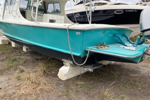 Slide: The Image of 1988 Robertson Sportfish boat in turquoise, resting on blocks, with visible interior and motor. - 6