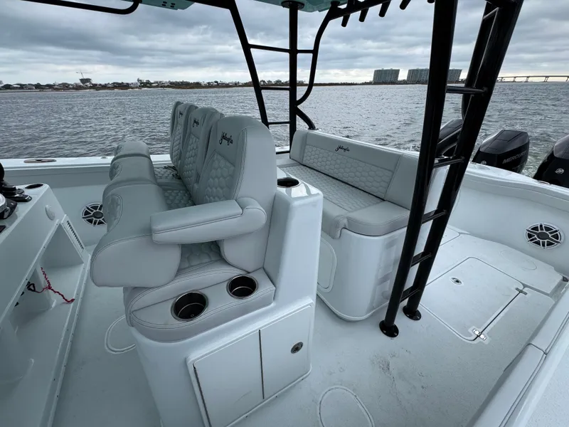 Slide: The Image of 2023 Yellowfin 42 Offshore boat interior with cushioned seating and cup holders on a calm water backdrop. - 45