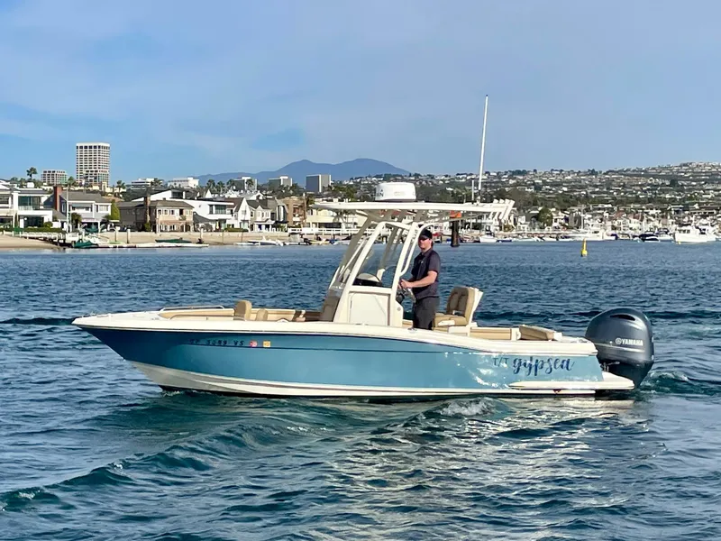 Slide: The Image of 2020 Scout 215 XSF boat cruising in a scenic coastal area. - 0