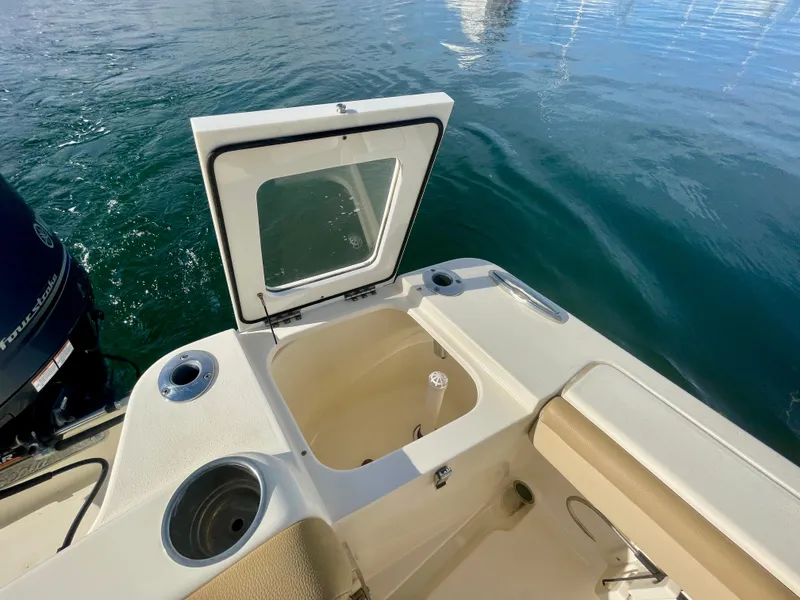 Slide: The Image of 2020 Scout 215 XSF boat with open storage compartment on calm water. - 12