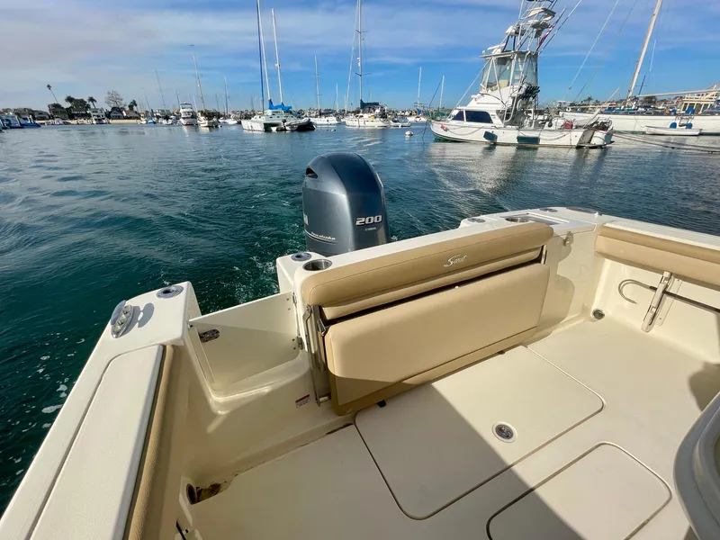 Slide: The Image of 2020 Scout 215 XSF boat in marina, featuring beige seating and outboard motor. - 14