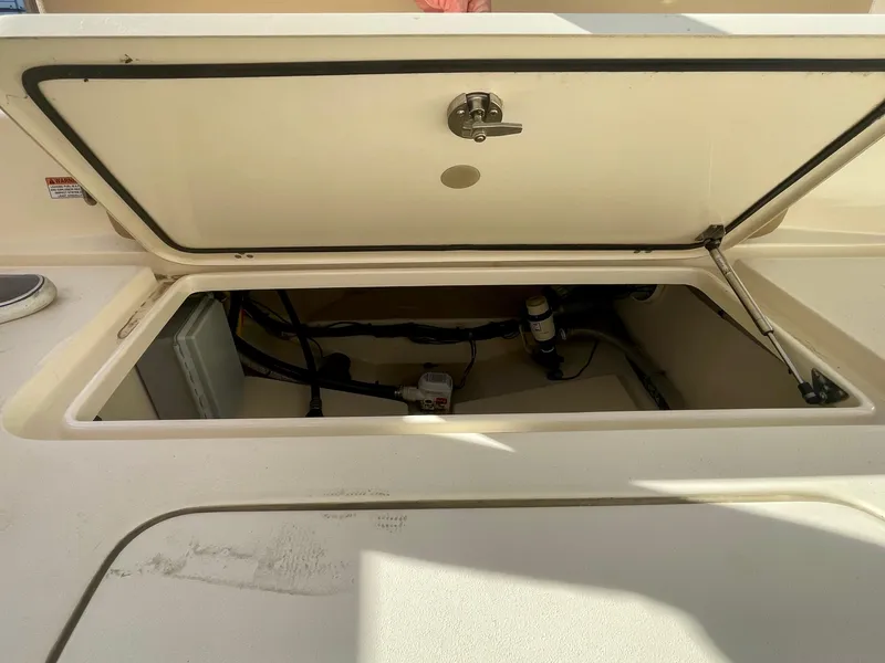 Slide: The Image of 2020 Scout 215 XSF boat storage compartment with open hatch and visible wiring. - 18