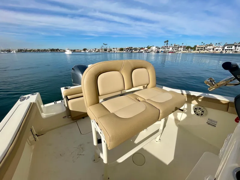 Slide: The Image of 2020 Scout 215 XSF boat interior with beige seating, docked on a calm waterfront. - 21