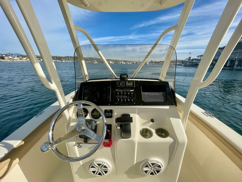 Slide: The Image of 2020 Scout 215 XSF boat dashboard with steering wheel, controls, and ocean view. - 25