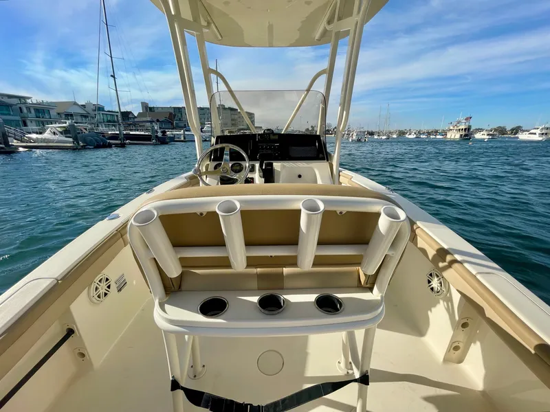 Slide: The Image of 2020 Scout 215 XSF boat interior with rod holders, steering wheel, and marina view. - 33