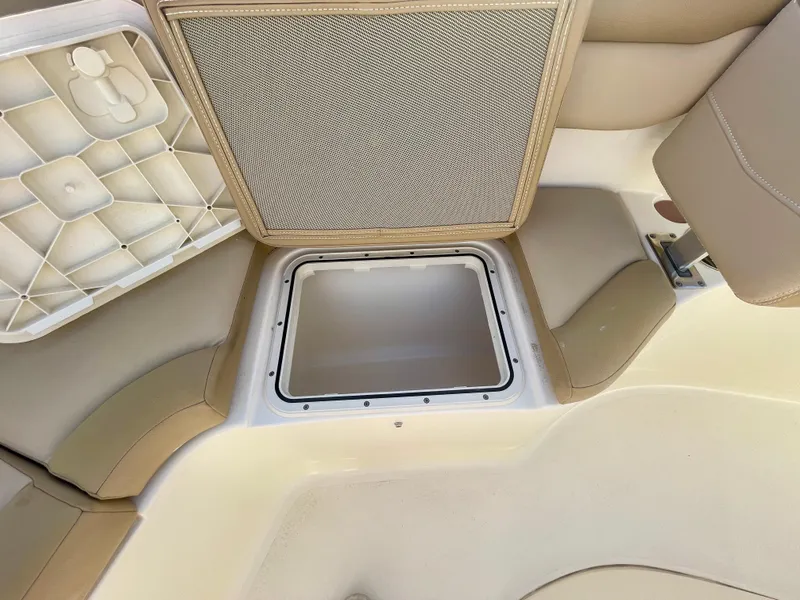 Slide: The Image of 2020 Scout 215 XSF boat storage compartment with beige seating and open hatch. - 8