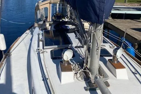 Slide: The Image of 1973 Tartan 34 sailboat deck with mast and solar panels, docked by the water. - 10