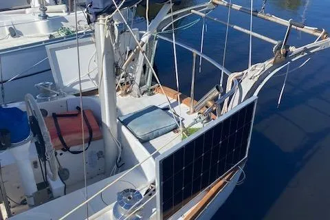Slide: The Image of 1973 Tartan 34 sailboat with solar panel on deck, docked on calm water. - 11