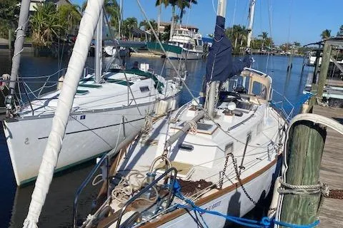 Slide: The Image of 1973 Tartan 34 sailboat docked in a sunny marina with palm trees. - 13
