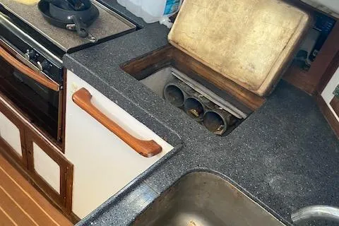 Slide: The Image of 1973 Tartan 34 yacht kitchen with stove, sink, and storage compartments. - 3