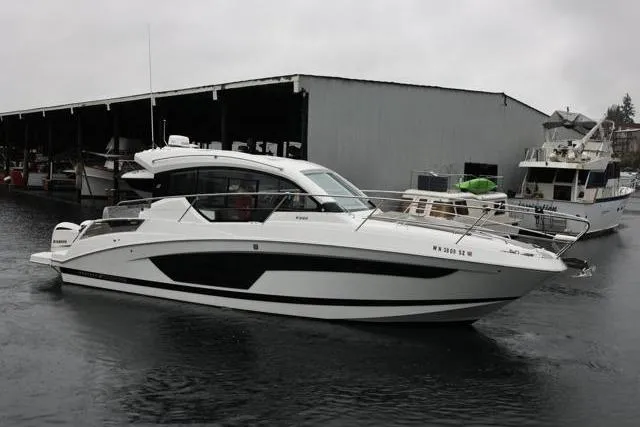 The Image of 2021 Four Winns V355 Coupe boat docked in a marina on a cloudy day. - 0