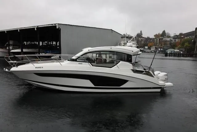 Slide: The Image of 2021 Four Winns V355 Coupe boat on water, overcast day, dock in background. - 24