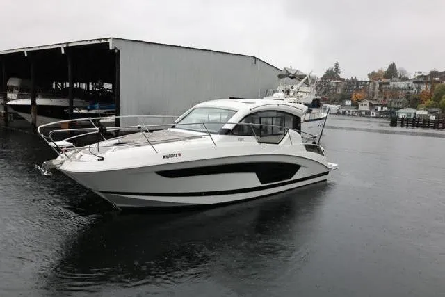 Slide: The Image of 2021 Four Winns V355 Coupe boat docked on a rainy day near a boathouse. - 26