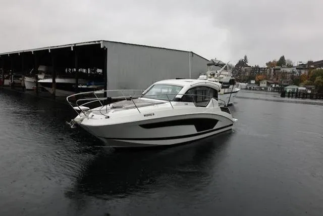 Slide: The Image of 2021 Four Winns V355 Coupe boat on water near dock, overcast sky. - 29