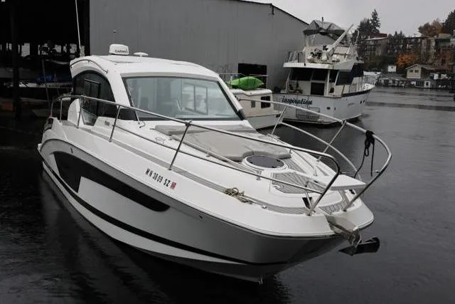 Slide: The Image of 2021 Four Winns V355 Coupe boat docked in a marina on a cloudy day. - 32